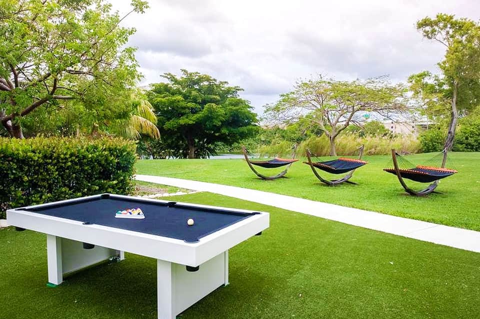 Lawn recreation area with pool table and hammocks under mature trees