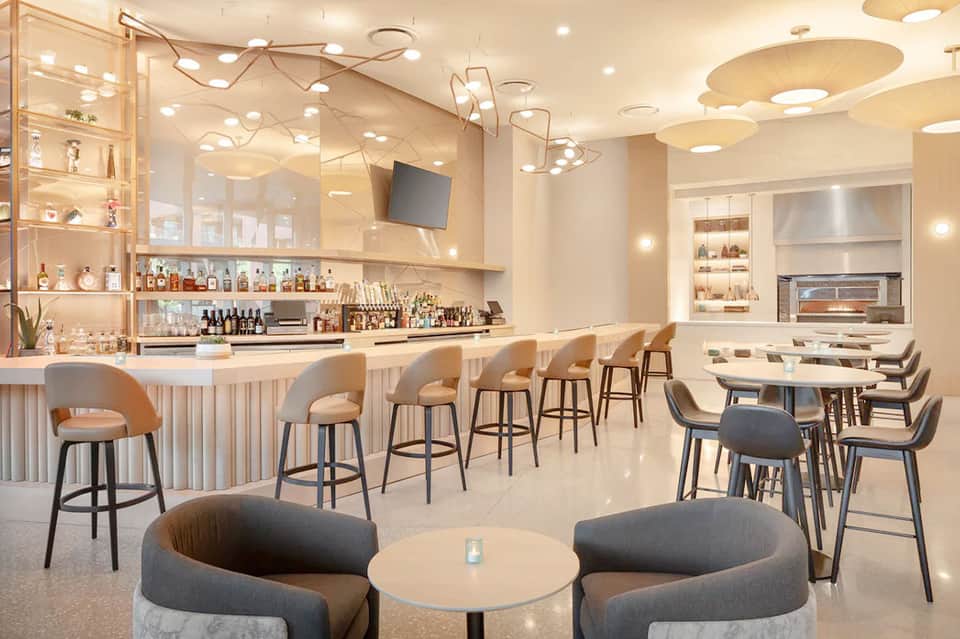 Modern resort bar and lounge area with beige seating and contemporary lighting