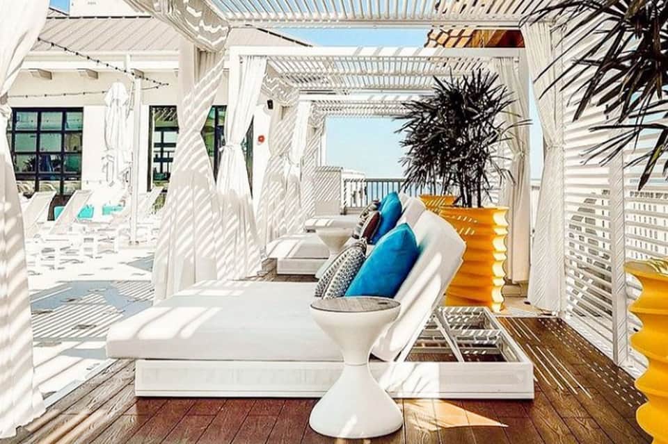 Modern white pergola lounge area with cushioned seating and ocean view from elevated deck
