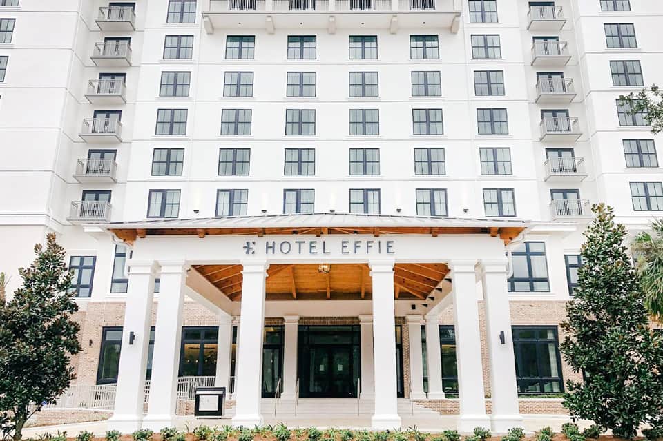 Hotel Effie white facade with wooden pergola entrance, brick accents and manicured landscaping