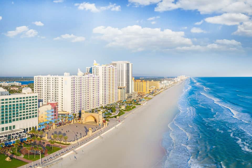 Aerial view of colorful beachfront resort buildings and sandy beach with ocean waves