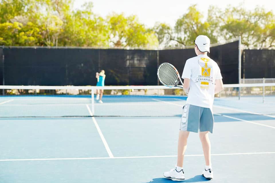 Tennis player on outdoor court during daytime match with spectators in background