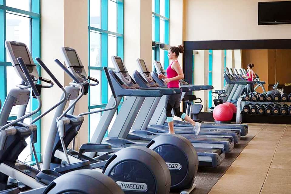 Bright fitness center with cardio equipment and large windows