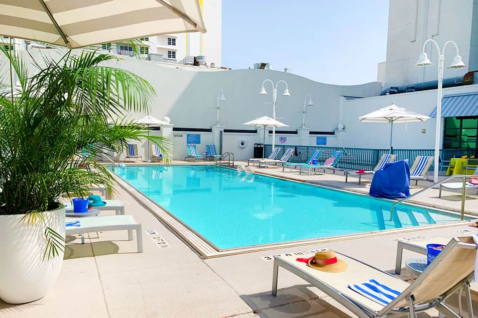 Resort swimming pool with blue and white striped loungers and white umbrellas