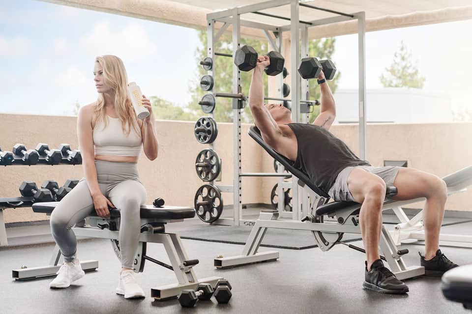 Rooftop gym with woman doing squats and man lifting dumbbells