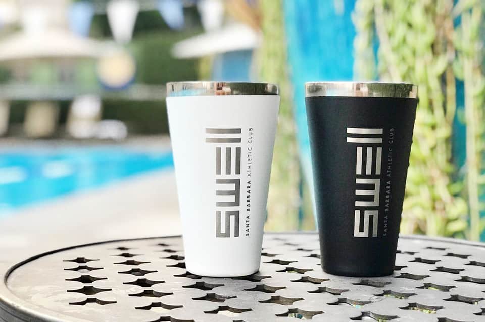 Two insulated travel cups with SWELL branding on patterned table by pool
