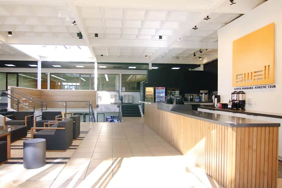 Contemporary athletic club lobby with reception desk, wooden accents, and lounge seating