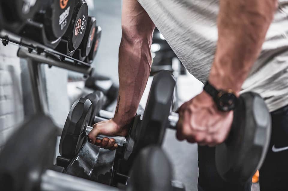 Man lifting dumbbells during strength training workout at gym facility