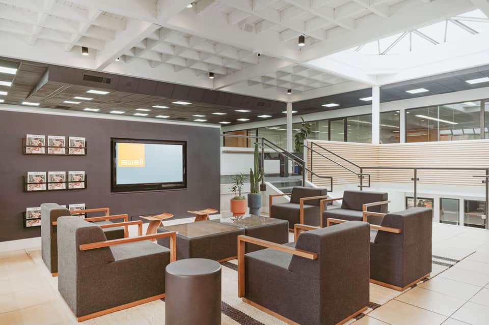 Modern hotel lobby lounge with gray armchairs, orange accents, and two-level open concept