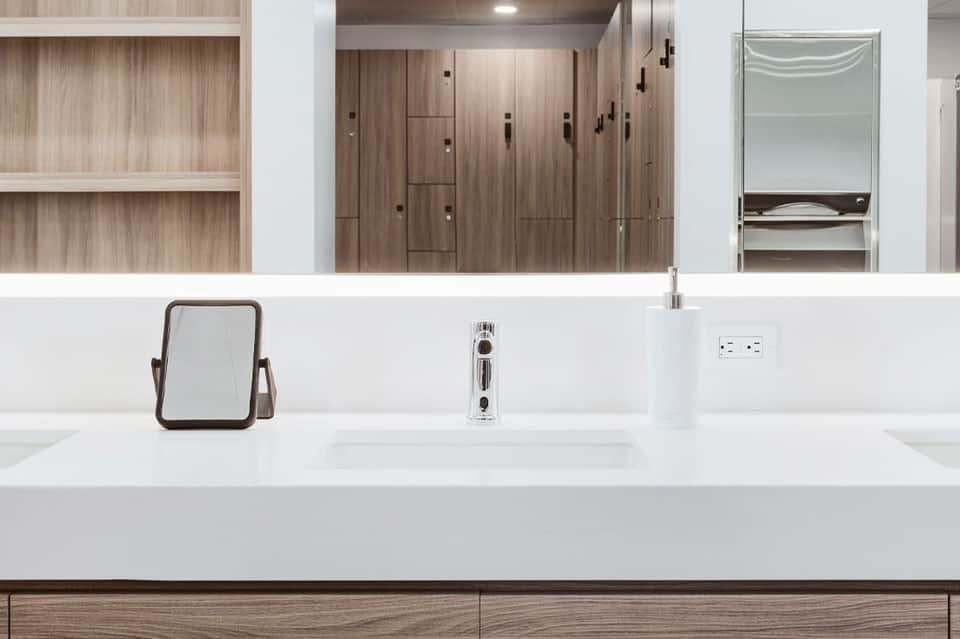 Modern bathroom vanity with white countertop, wooden cabinetry, and chrome fixtures