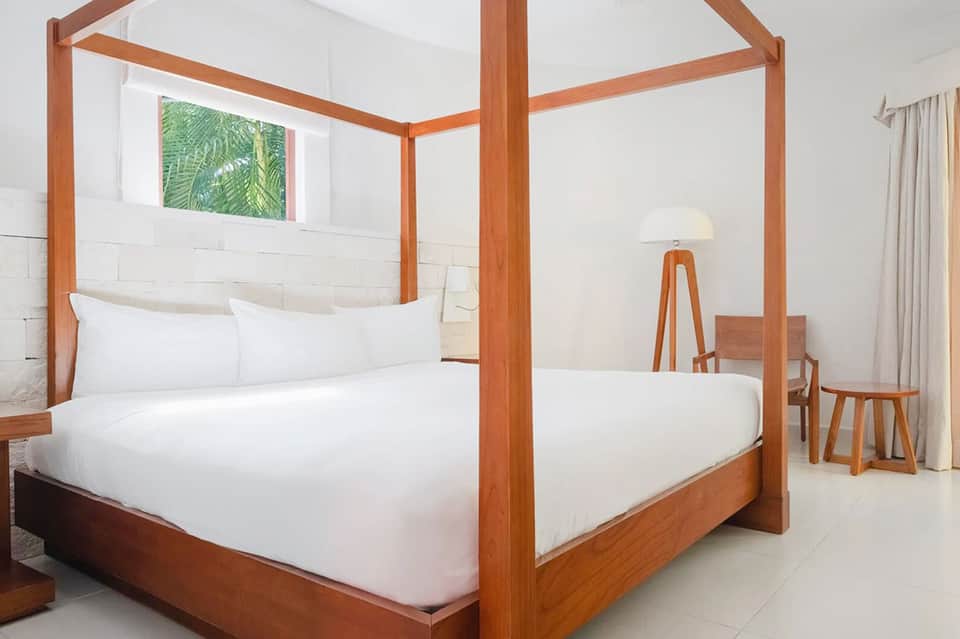 Contemporary bedroom with wooden four-poster bed and tropical window art