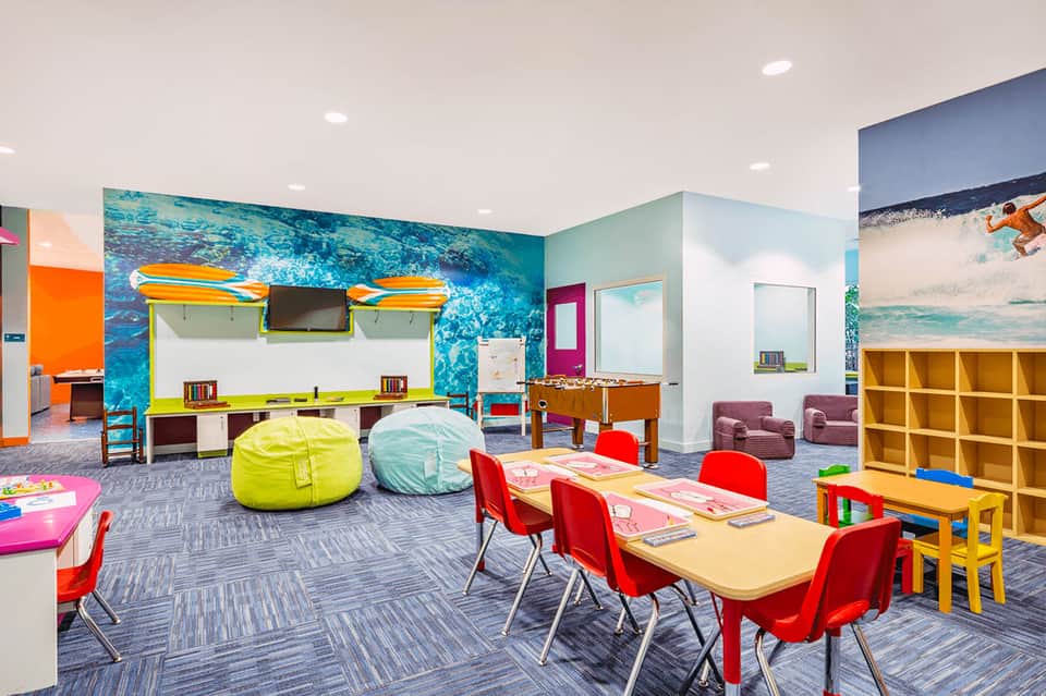 Colorful children's activity room with bean bags, tables, and educational murals