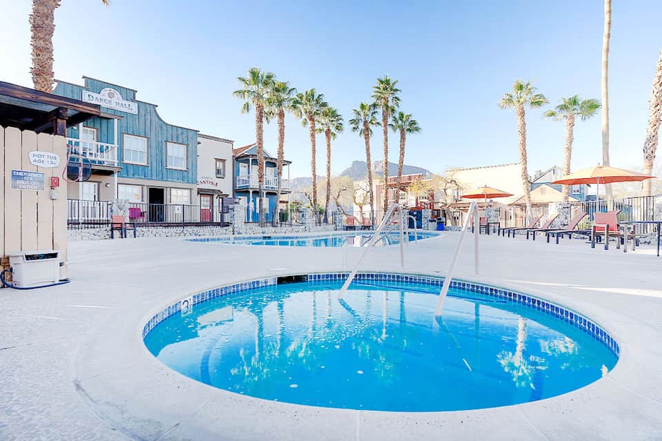 Circular blue pool in resort courtyard with palm trees and colorful buildings