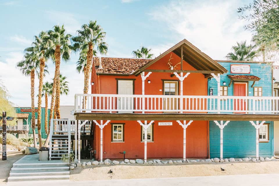 Colorful beachfront cottage painted orange and turquoise with white railings