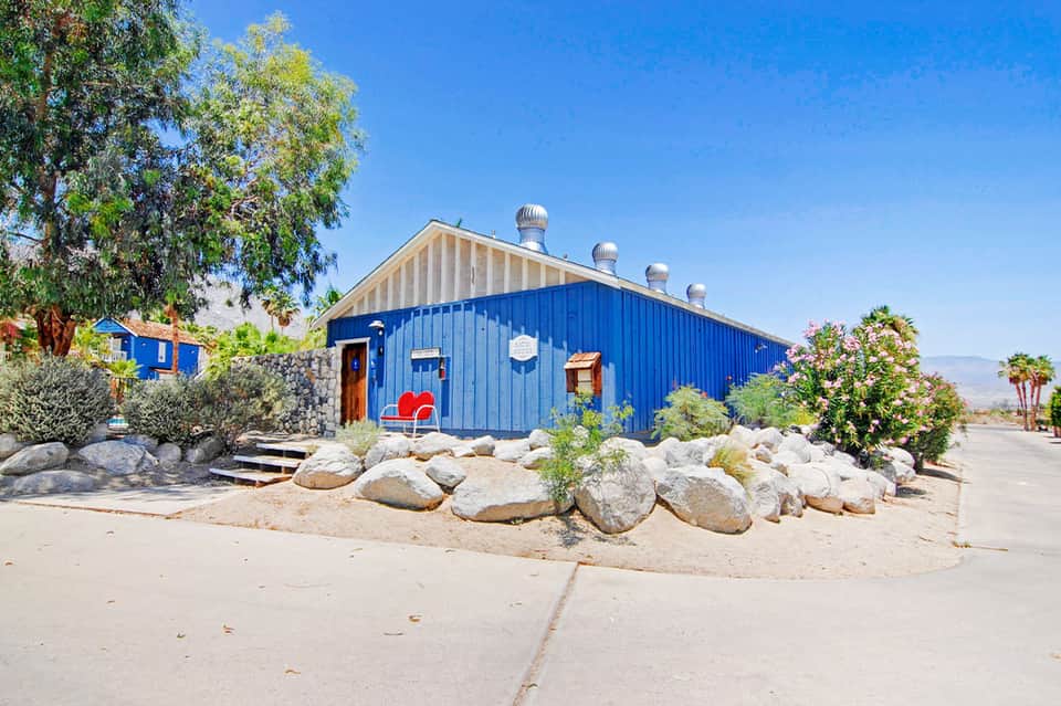 Blue modernist building with red accents in desert landscape