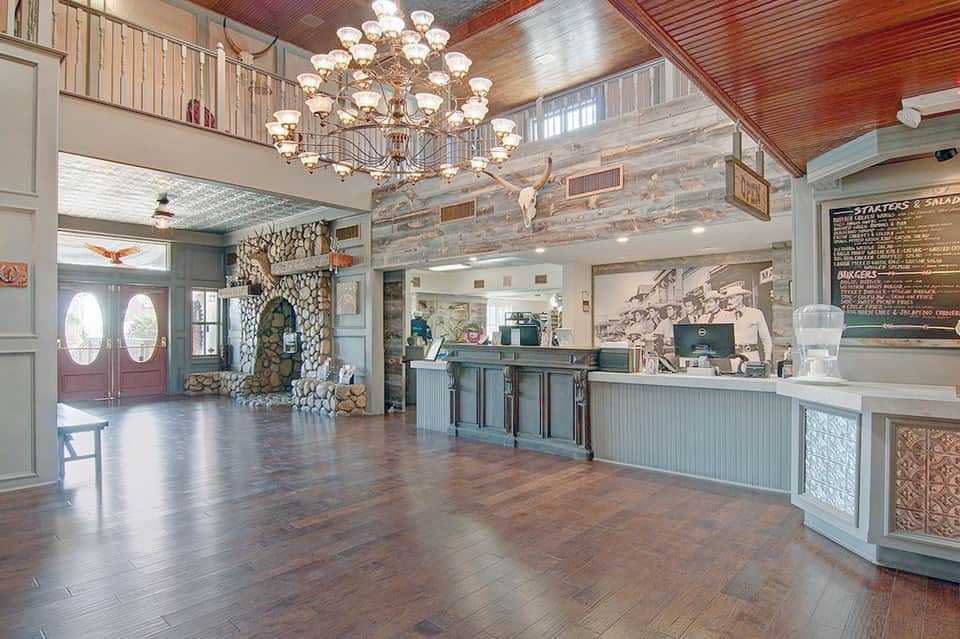 Spacious hotel lobby with high ceilings, chandelier, stone fireplace, and reception desk