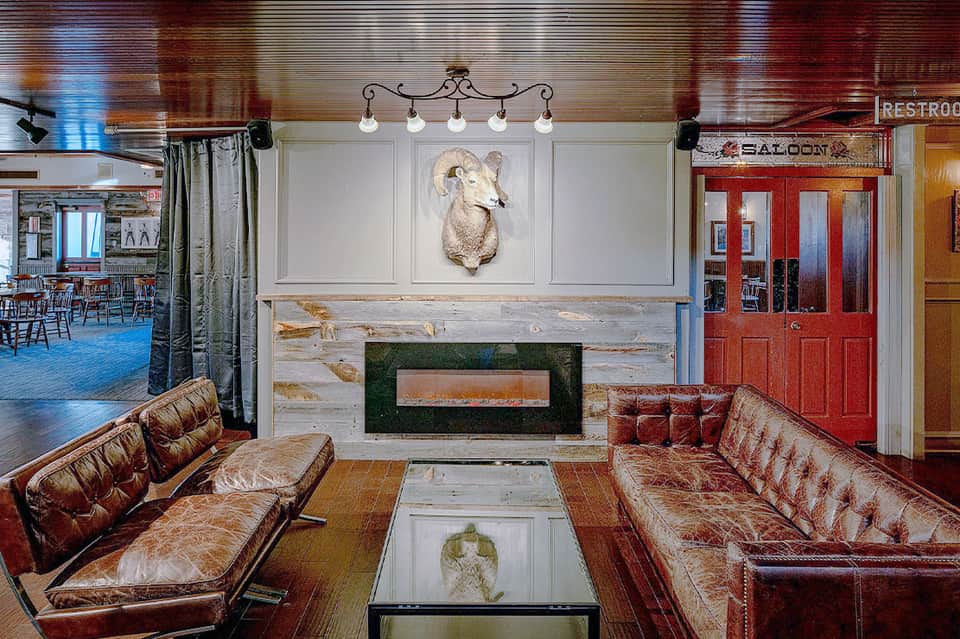 Elegant lounge area with leather seating, fireplace, and saloon entrance