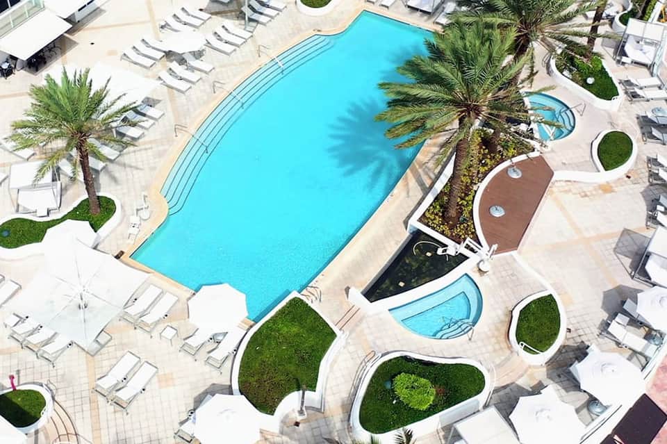 Overhead view of large rectangular resort pool with lounge chairs and manicured grounds