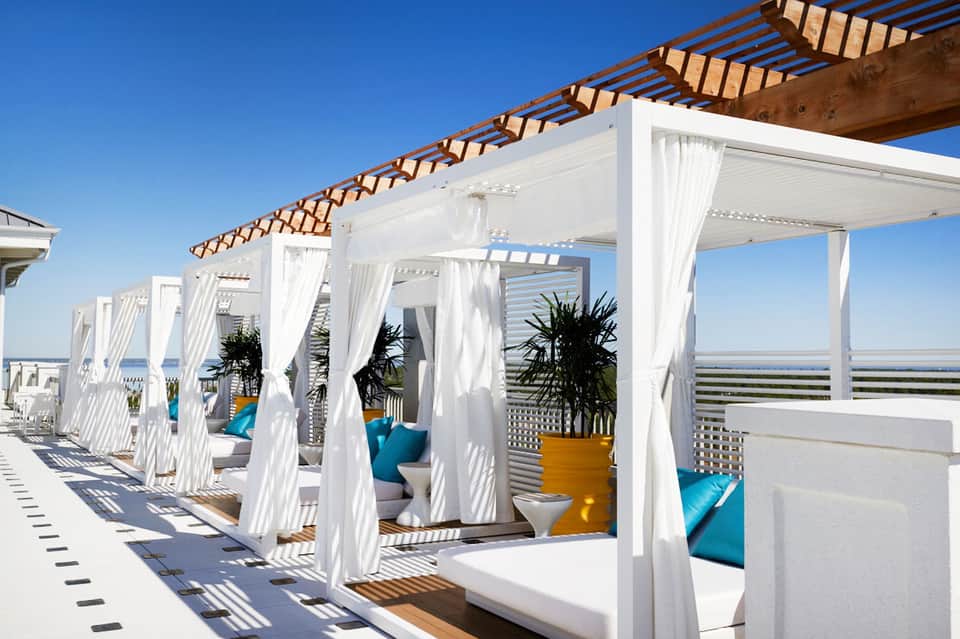 White pergola cabanas with flowing curtains and wooden beams on rooftop terrace