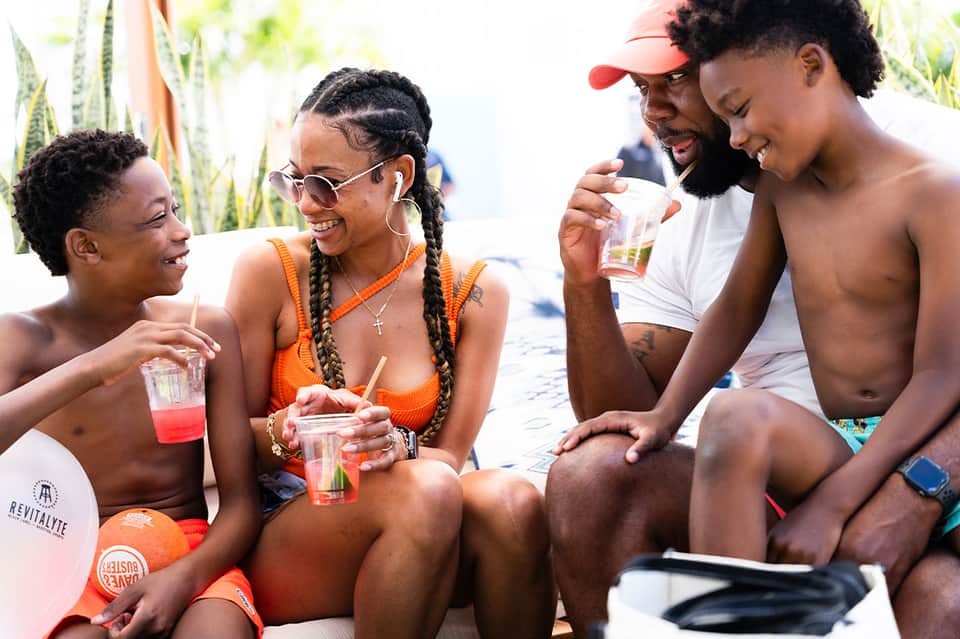 Group of young adults enjoying tropical drinks and socializing at a beachside resort during daytime