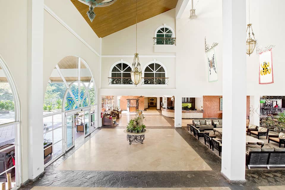 Modern hotel lobby with high ceilings, white columns, and ocean views through large windows