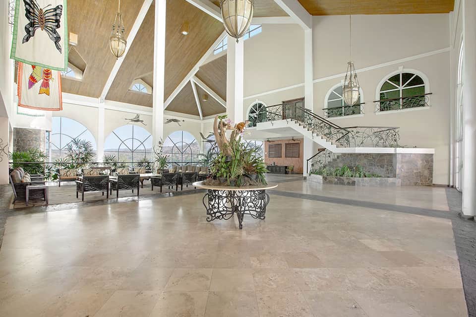 Grand lobby atrium with soaring ceiling, skylights, decorative plants, and two-story windows