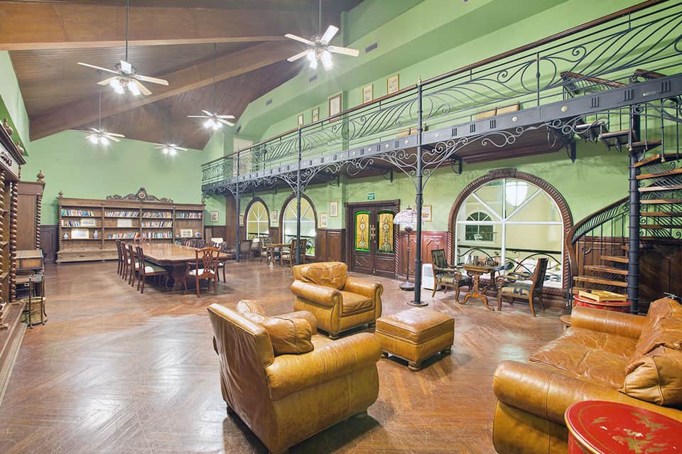 Historic grand lobby with ornate iron railings, leather seating, and high vaulted ceiling