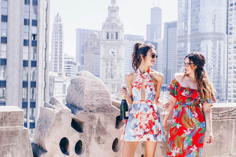 Two women in colorful dresses on a rooftop with Chicago skyline and clock tower backdrop