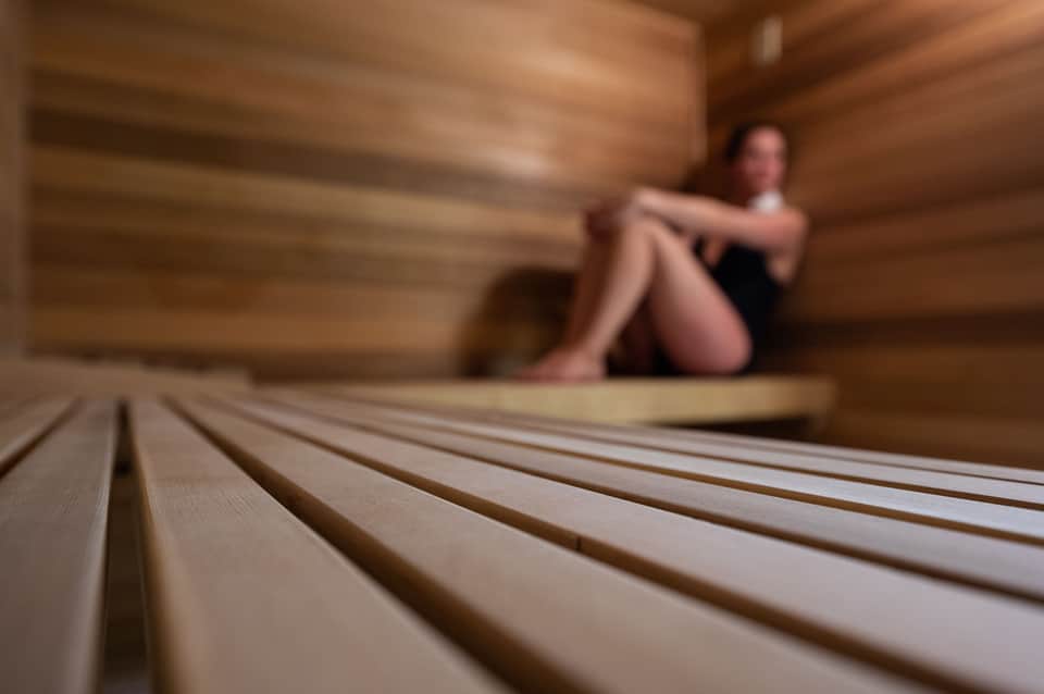 Close-up of wooden sauna bench with blurred figure in background