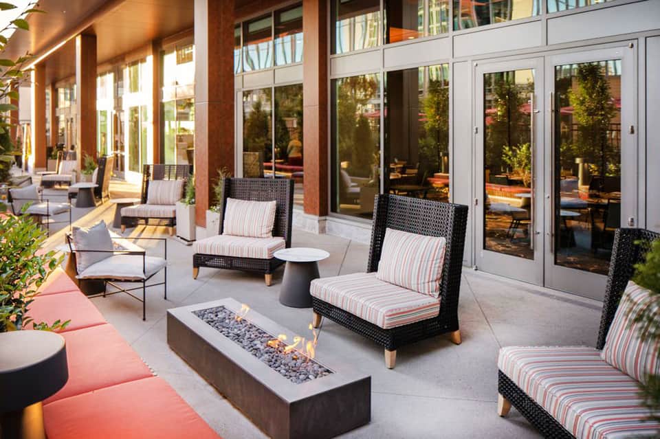 Contemporary patio with lounge chairs, striped cushions, fire pit, and glass doors overlooking landscaped grounds