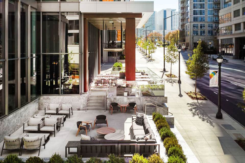 Urban courtyard with modern seating areas, fireplace, and city skyline view through glass doors