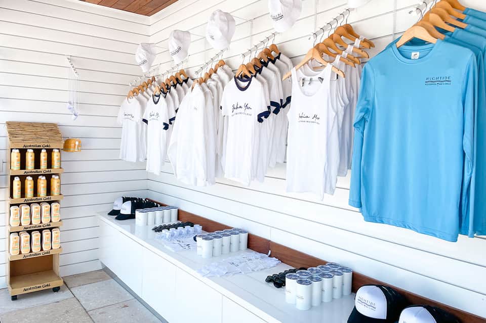 Retail shop displaying white t-shirts and blue merchandise on wooden hangers