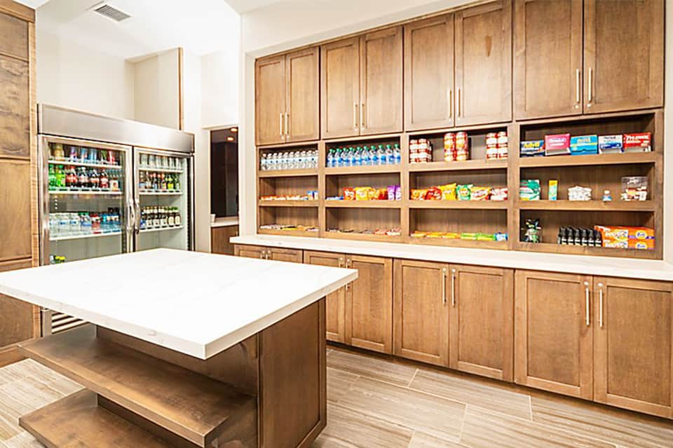 Luxury pantry with wood cabinetry, white quartz countertop, refrigerated beverage cooler, and organized snack shelving