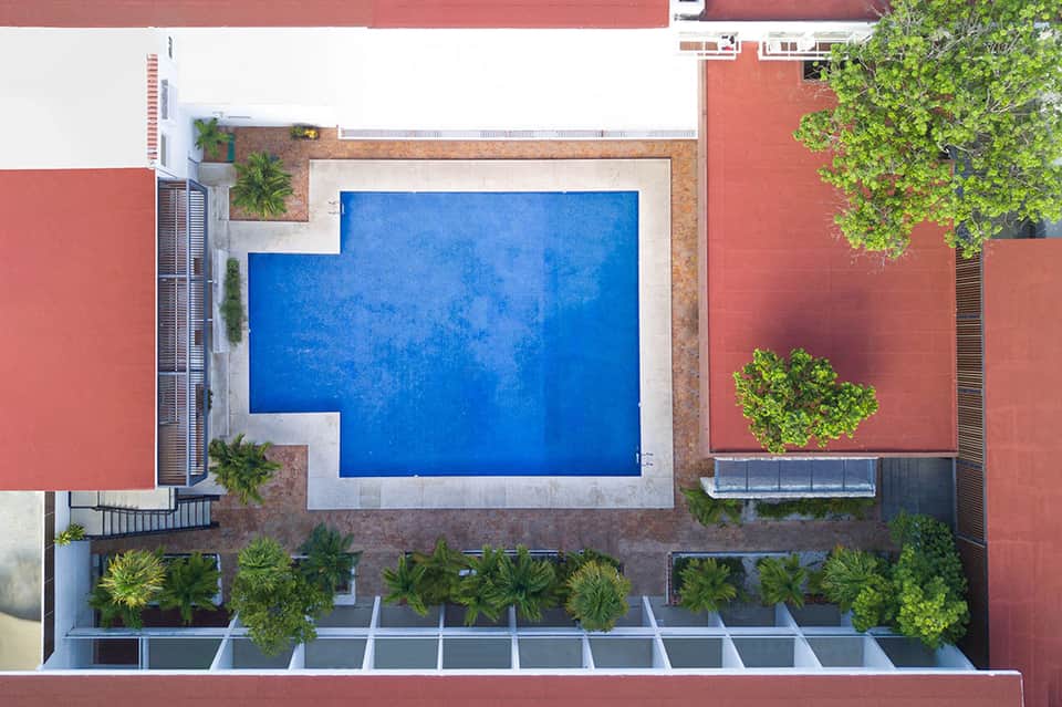 Aerial view of bright blue rectangular pool surrounded by red brick walls and green landscaping