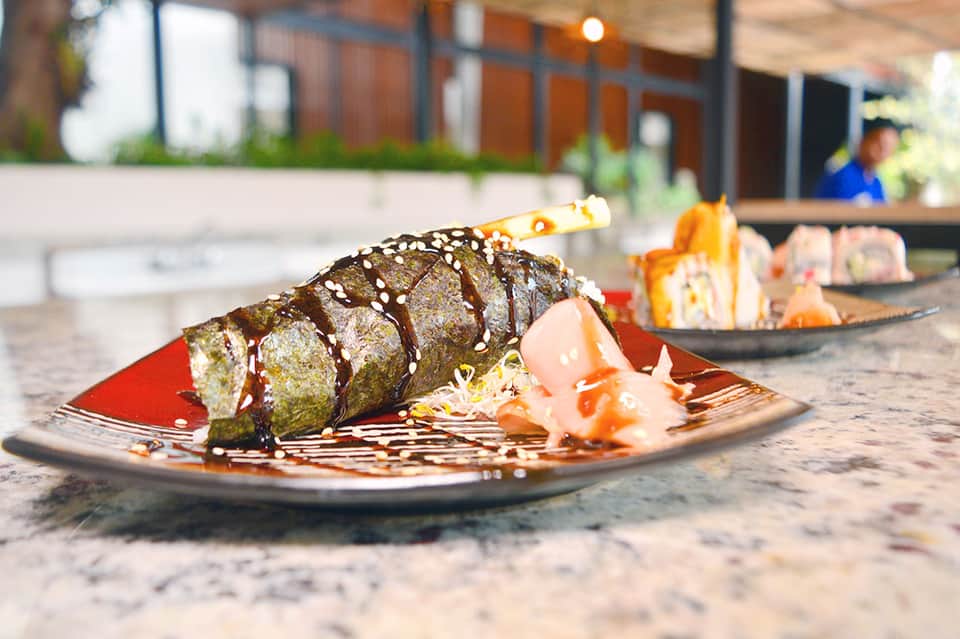 Gourmet plated dish with gold-wrapped item and chocolate drizzle on outdoor patio