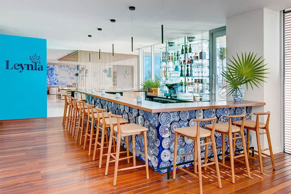 Modern bar with blue accent wall, wooden seating, and extensive bottle display at Leynla resort