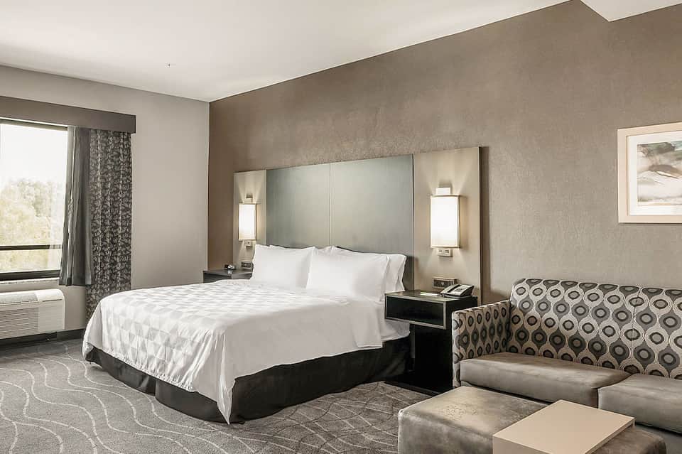 Modern hotel bedroom with white bedding, neutral walls, and contemporary furnishings