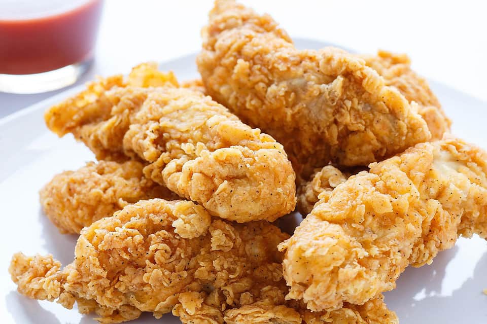Golden fried chicken pieces served on a white plate with sauce