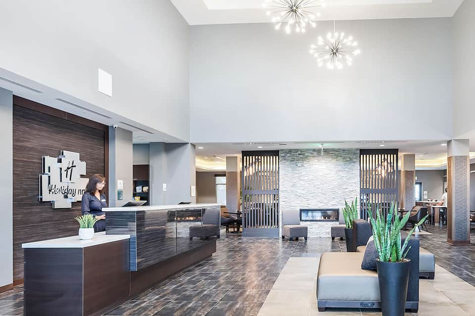 Contemporary hotel lobby with dark wood reception desk, modern lighting, and seating area