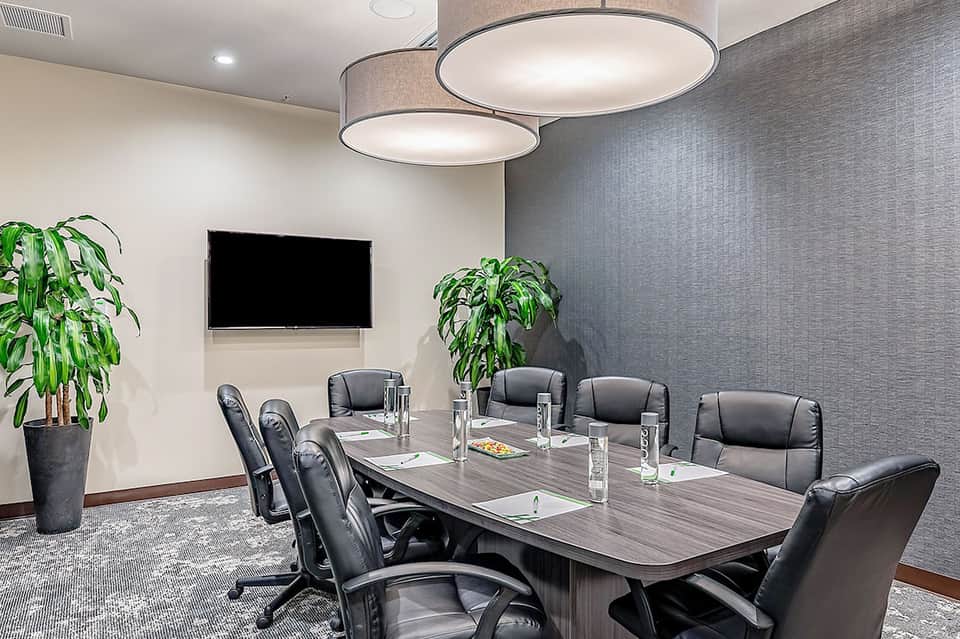 Professional conference room with long table, black chairs, and presentation screen