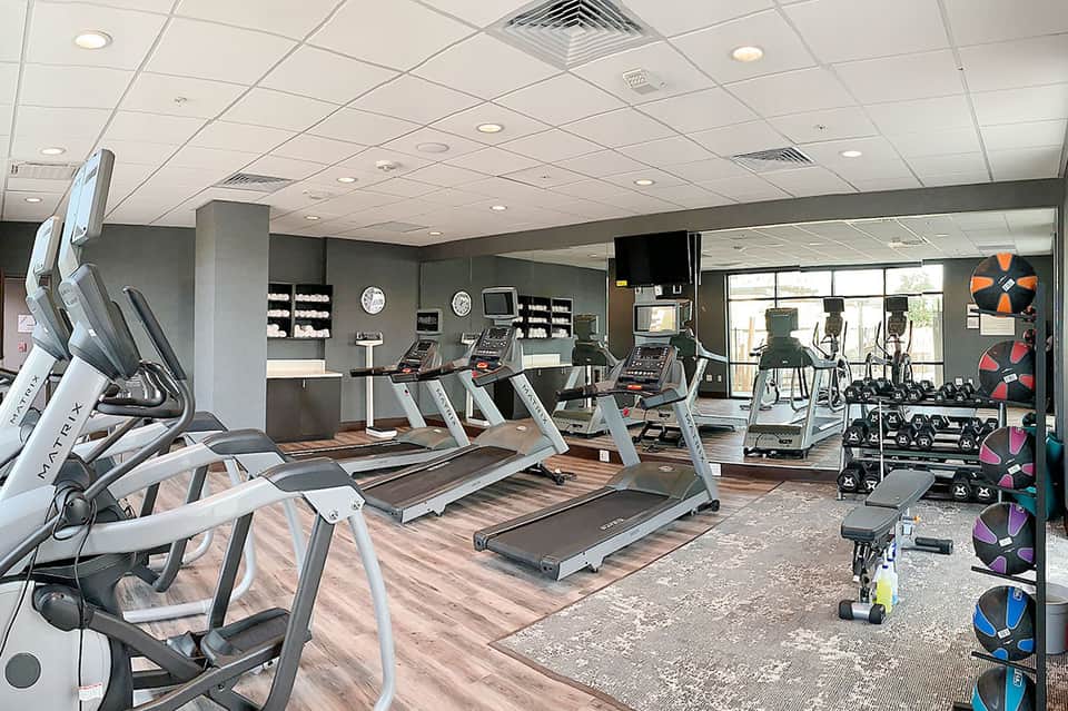 Modern hotel fitness center with treadmills, exercise equipment, and floor-to-ceiling windows