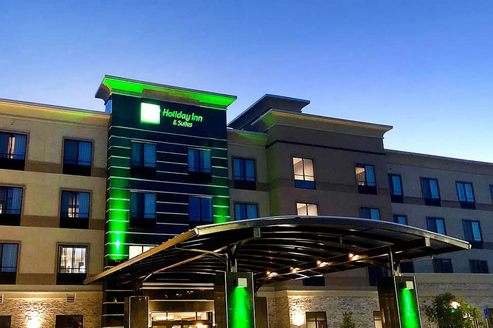 Holiday Inn & Suites exterior with green neon signage and modern building design at night