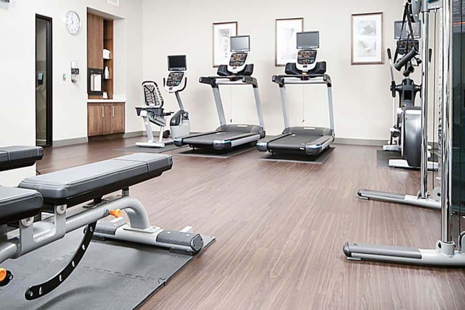 Fitness center with treadmills, exercise bikes, weights, and wooden flooring