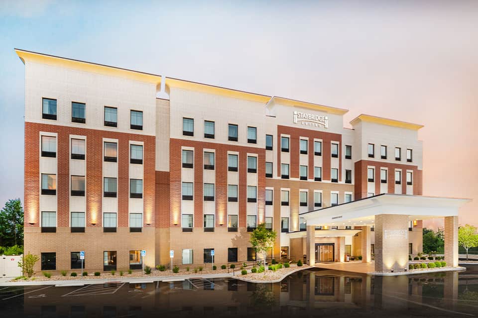 Staybridge Suites hotel exterior at dusk with brick and stone facade and entrance portico