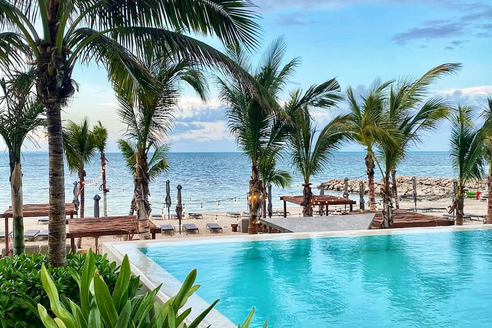 Tropical beach resort with palm trees, lounge chairs, and turquoise ocean view