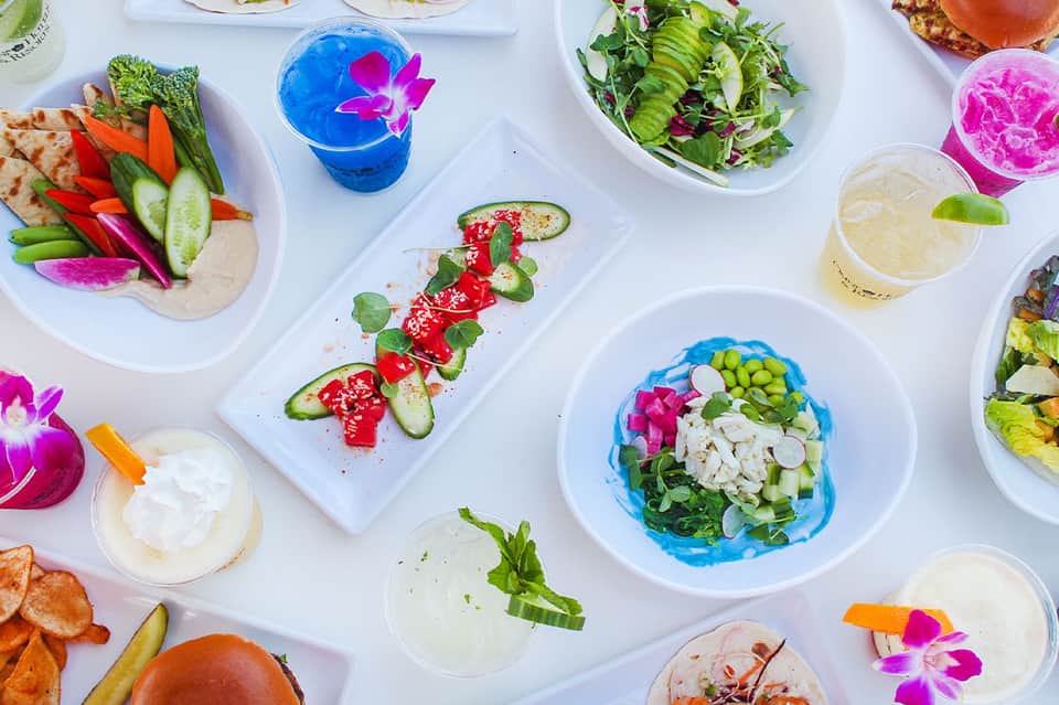 Overhead view of gourmet plated dishes with edible flowers and colorful beverages