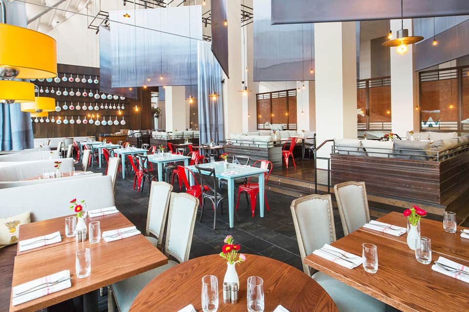 Modern restaurant interior with high ceilings, red chairs, and contemporary design