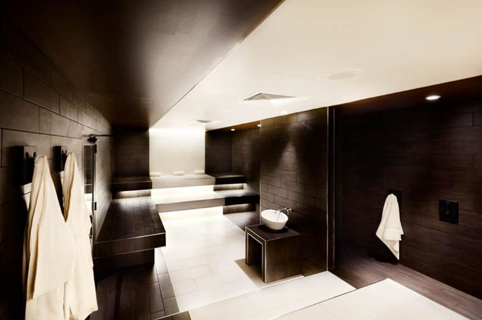 Upscale spa bathroom with black tile, white tub, and ambient lighting