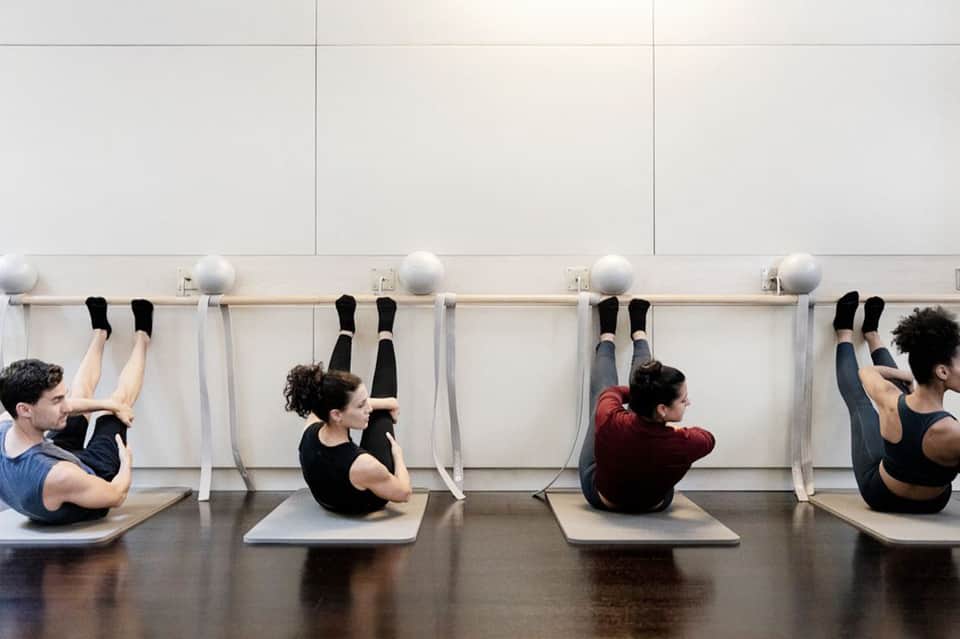 Group fitness class doing core exercises with stability balls against wall