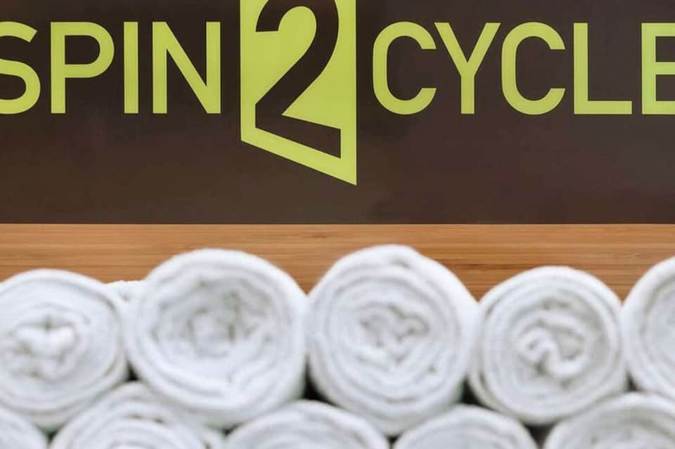 Spin2Cycle fitness facility sign with rolled white towels stacked below